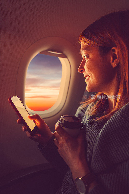 年轻女子在飞机上发短信，喝咖啡