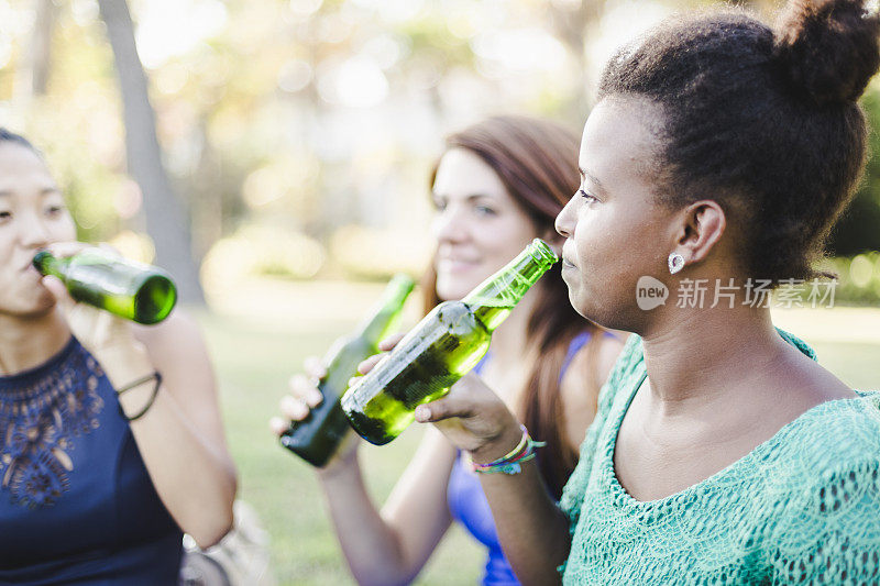 三个年轻女人在公园喝啤酒