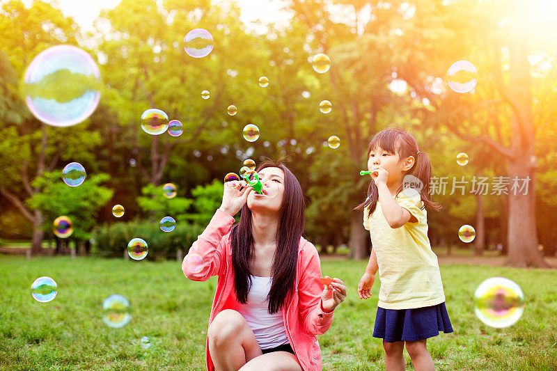 妈妈和女儿在公园和肥皂泡玩得开心
