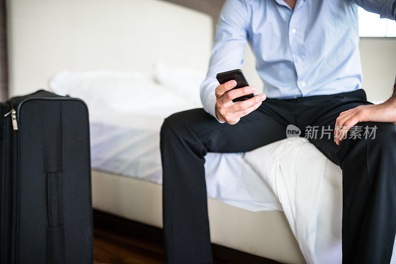 沉思的男人坐在床上看手机