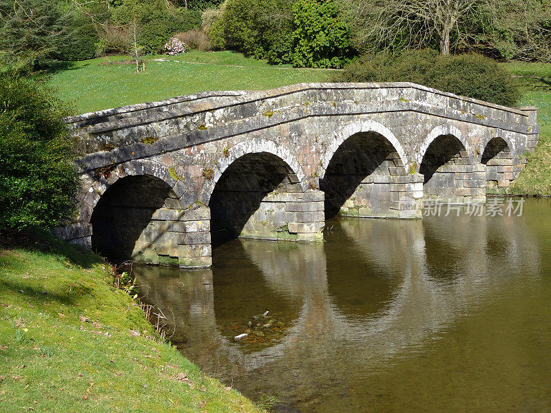古老的石桥和拱门倒影在河上的形象