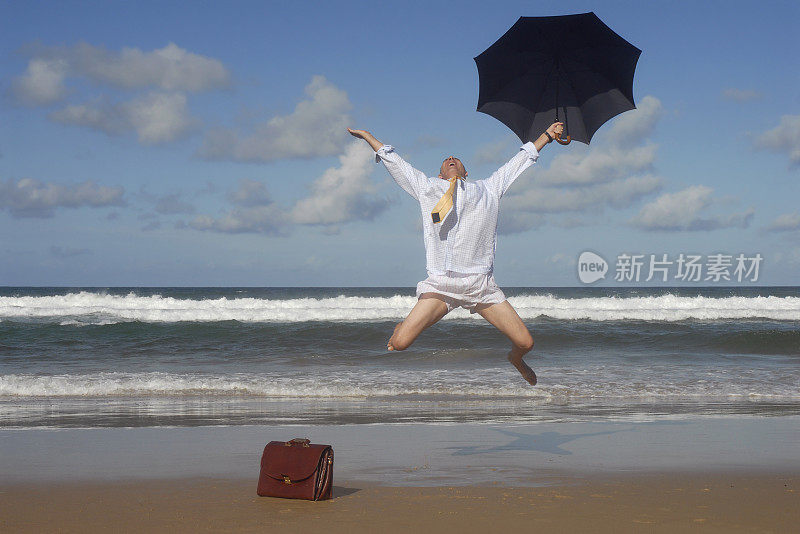 快乐的商人在热带海滩上跳起来