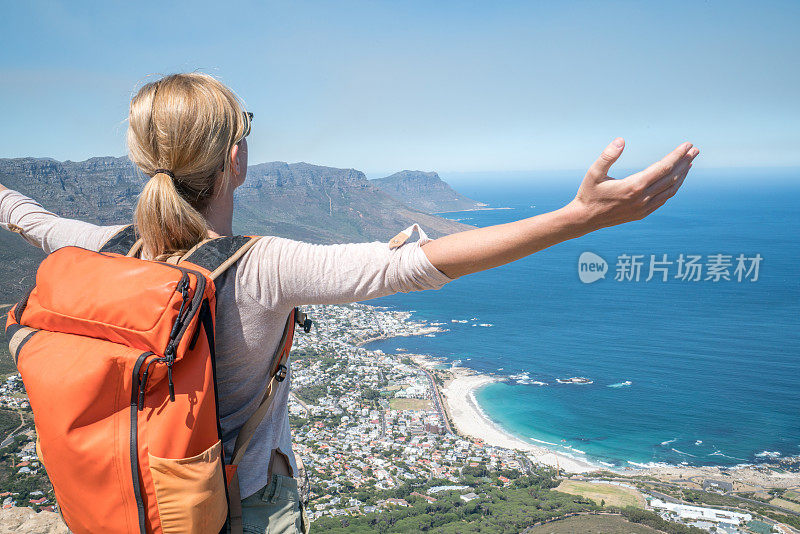 开普敦的一位年轻女子站在山顶，双臂张开