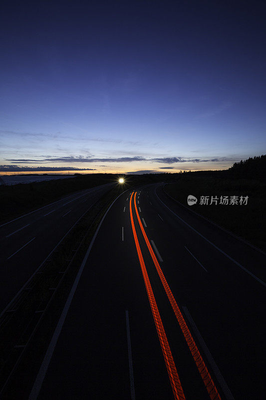 公路上的夜晚:夜幕降临后，公路上出现了灯光