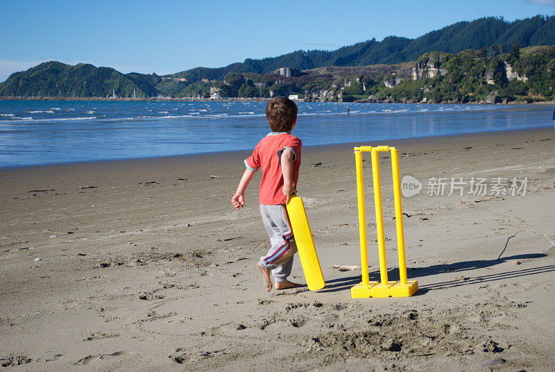 男孩在沙滩上打板球