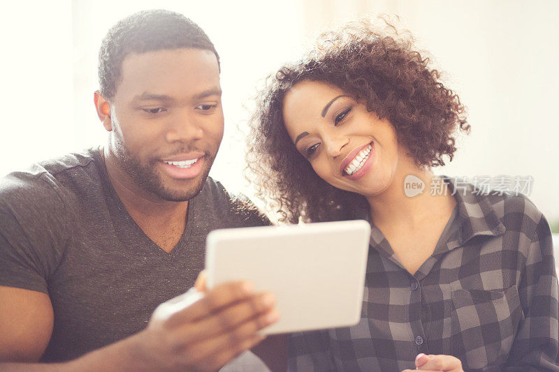 快乐的非洲裔美国夫妇在家里使用数码平板电脑