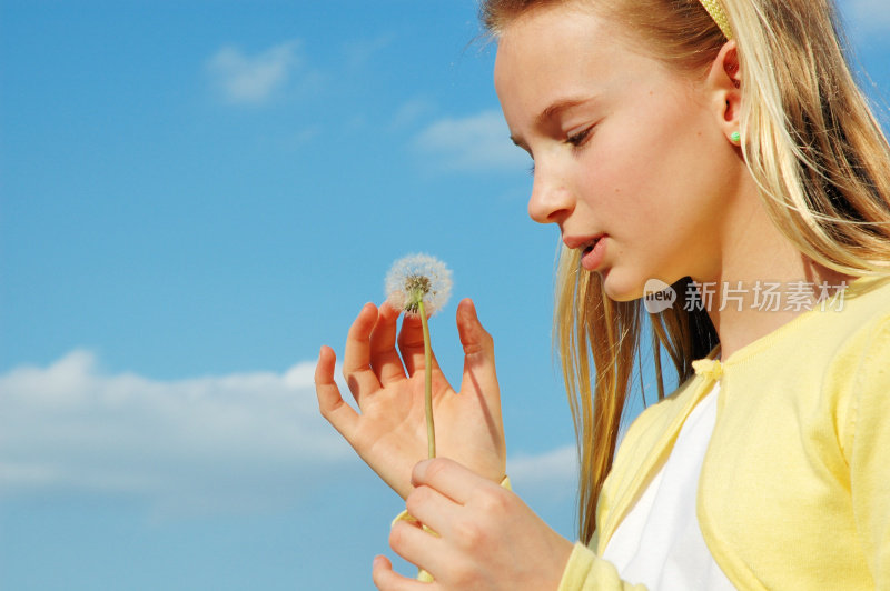 年轻的女孩在蒲公英下许愿