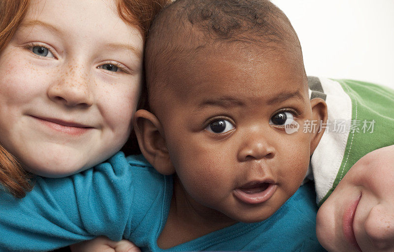 小学红发女孩抱着6个月大的黑人领养妹妹