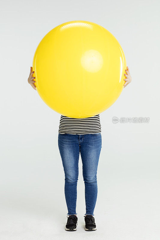 年轻女子拿着黄色的大气球