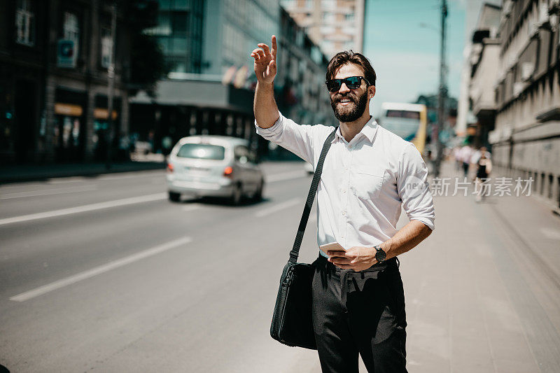 一个穿着商务服的年轻人向出租车招手