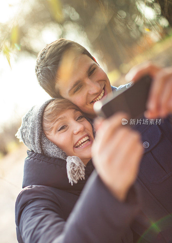 快乐的青少年情侣用智能手机拍照