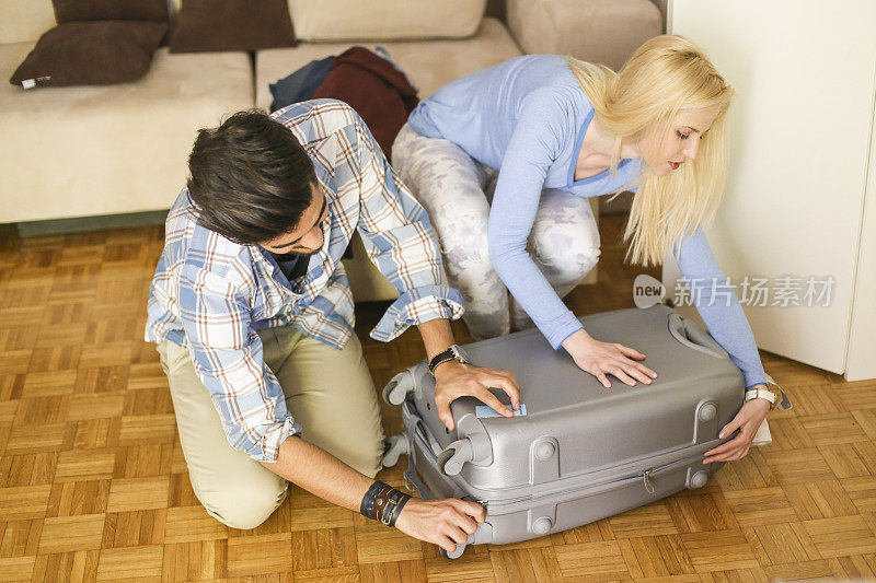 一对年轻夫妇正在打包度假的行李箱