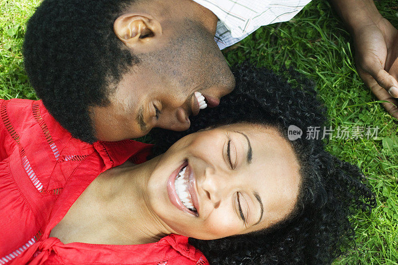 年轻夫妇头对头，微笑着躺在草地上