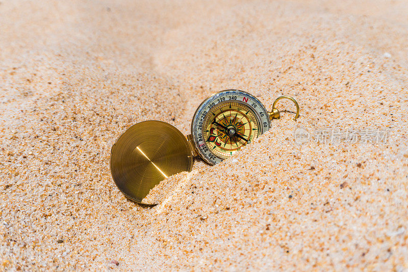 指南针在沙滩上的金色沙滩上。夏天的时间