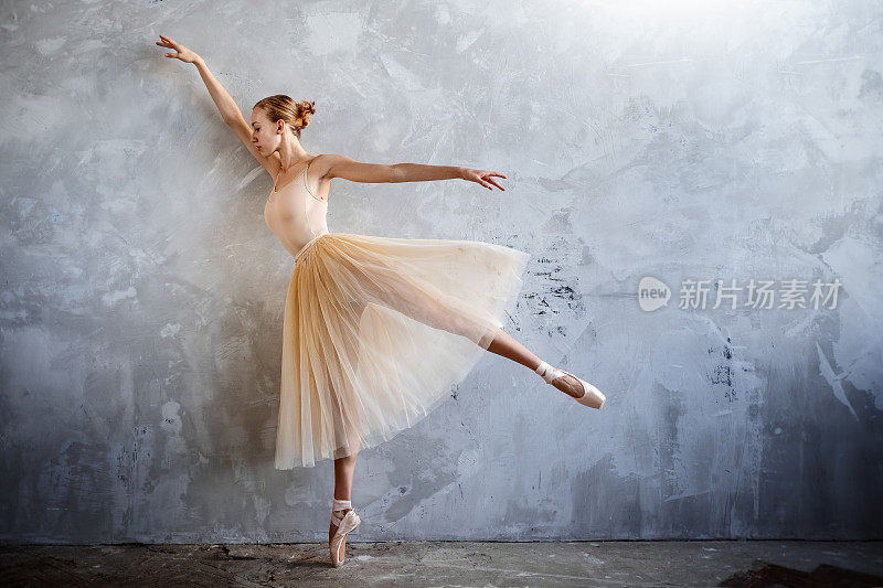 年轻的芭蕾舞演员穿着金色的舞蹈服装在阁楼工作室摆姿势