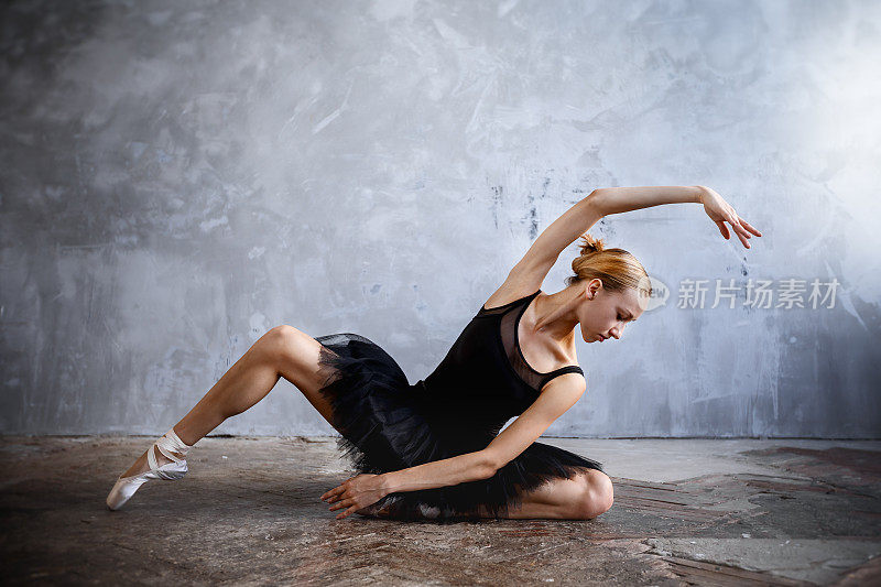 年轻的芭蕾舞女演员穿着黑色舞蹈服在阁楼工作室摆姿势