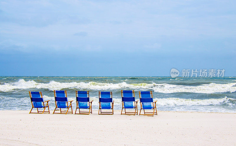 白色沙滩和蓝色沙滩椅的热带海滩。