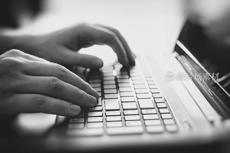 男性的手放在笔记本电脑的键盘上