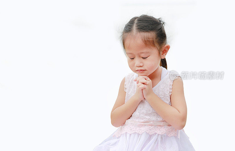 闭上眼睛小亚洲女孩祈祷孤立在白色的背景。