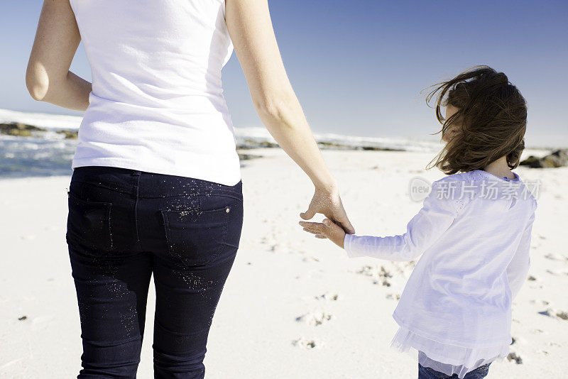小女孩拉着妈妈的手走下海滩的背影