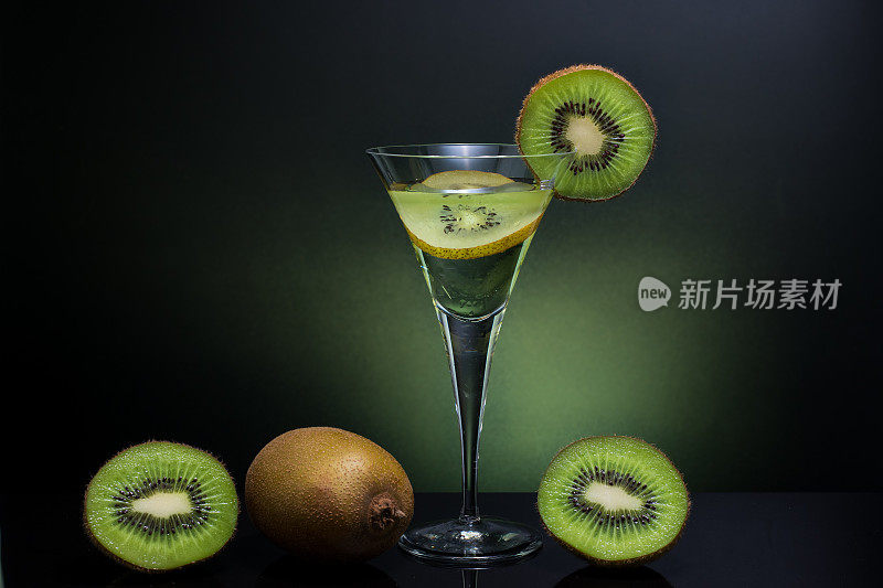 绿色猕猴桃饮料，冷清的饮料在高脚杯与整个猕猴桃背景