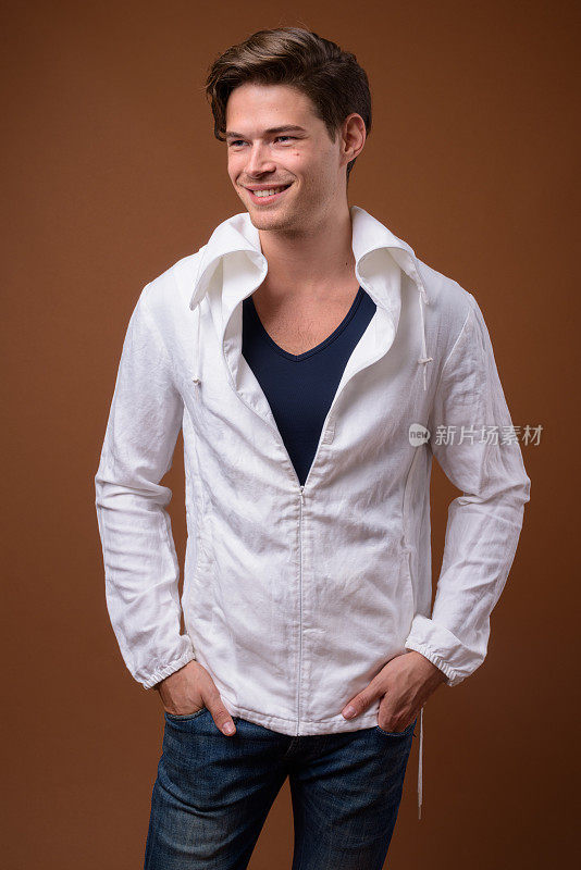 工作室拍摄的年轻英俊的男子穿着高领白色夹克，以彩色背景