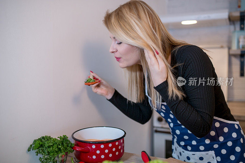 年轻女子在厨房里做饭，站在炉子旁边