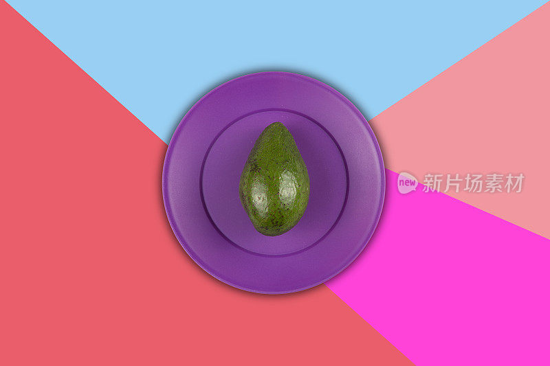 紫色塑料盘子里的牛油果，背景是彩色的。