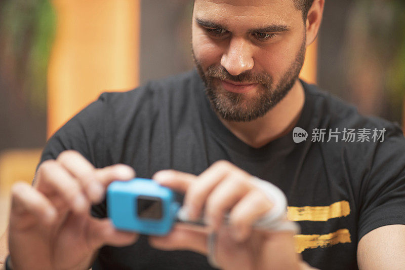 蓄着胡须的英俊男子用动作摄像机拍摄，在咖啡馆餐厅的咖啡休息时间用GoPro相机