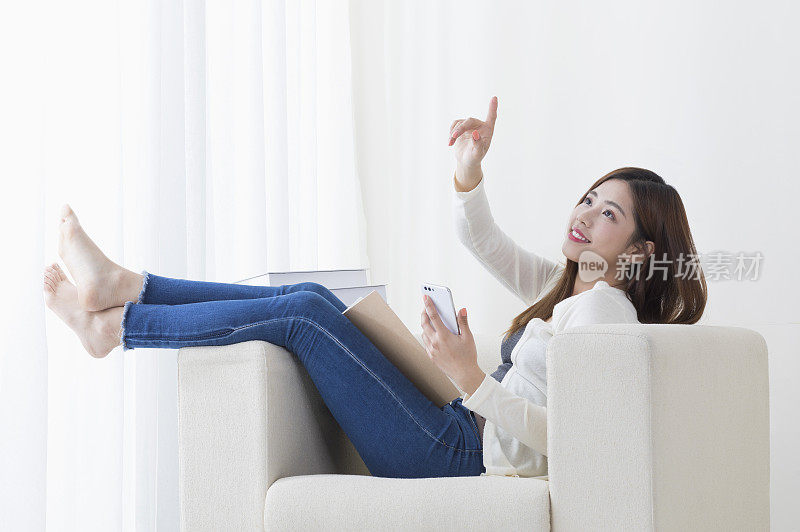 年轻女人坐在沙发上使用手机
