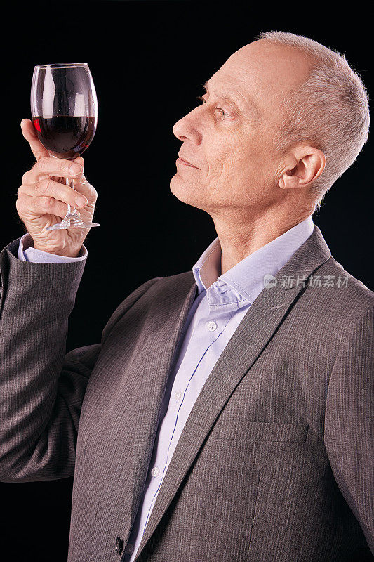 成熟的男人捧着一杯红酒，认真地品酒
