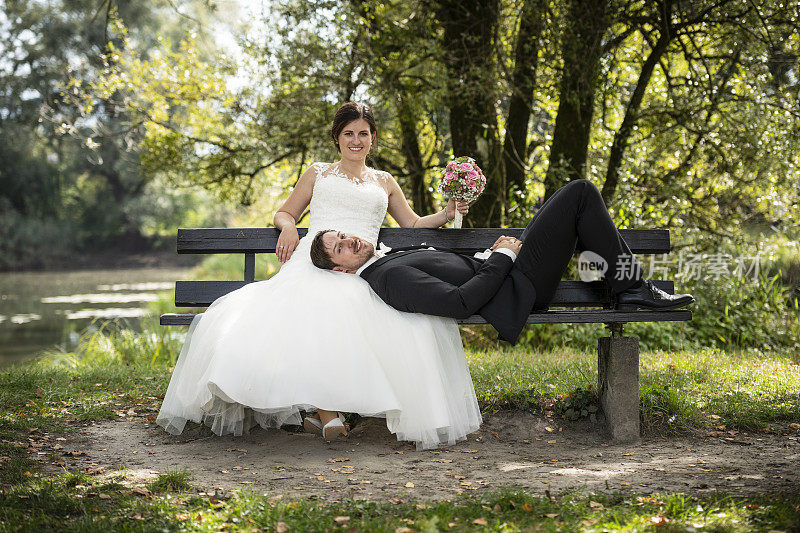 刚刚结婚的新娘和新郎坐在长椅上