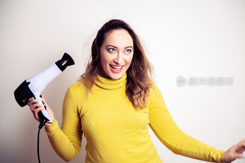 年轻微笑的女人用吹风机把头发卷起来