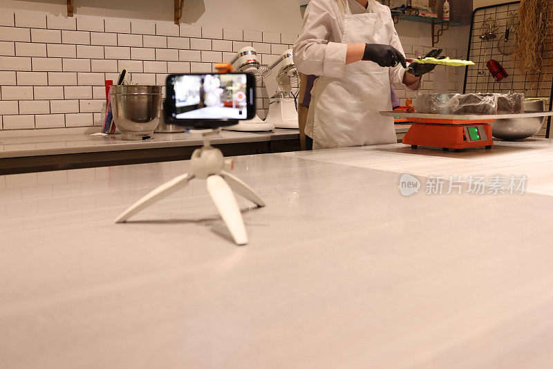 一位女厨师一边做饭一边用手机录制视频。