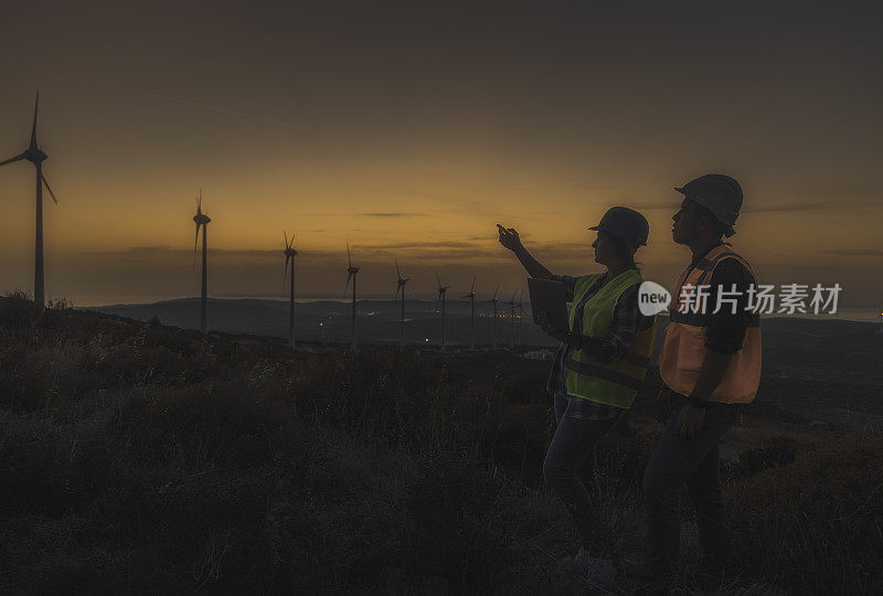 日落时分，维修工程师团队在风力发电厂工作