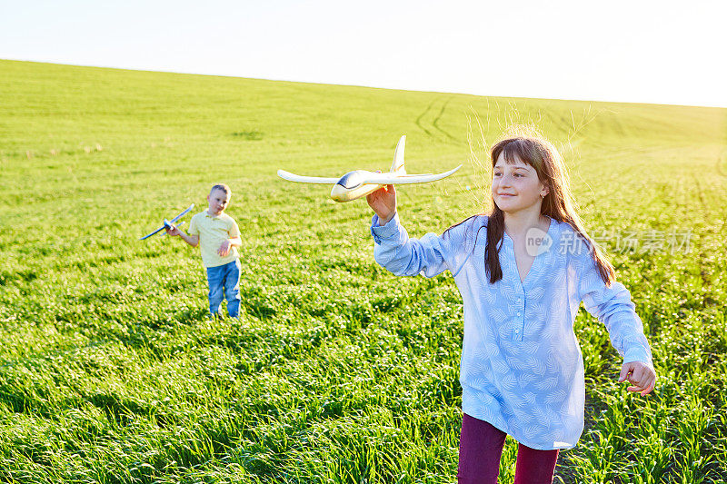 欢快快乐的孩子们在田野里玩耍，想象着自己是阳光明媚的夏日里的飞行员。孩子们梦想着飞行和飞行。