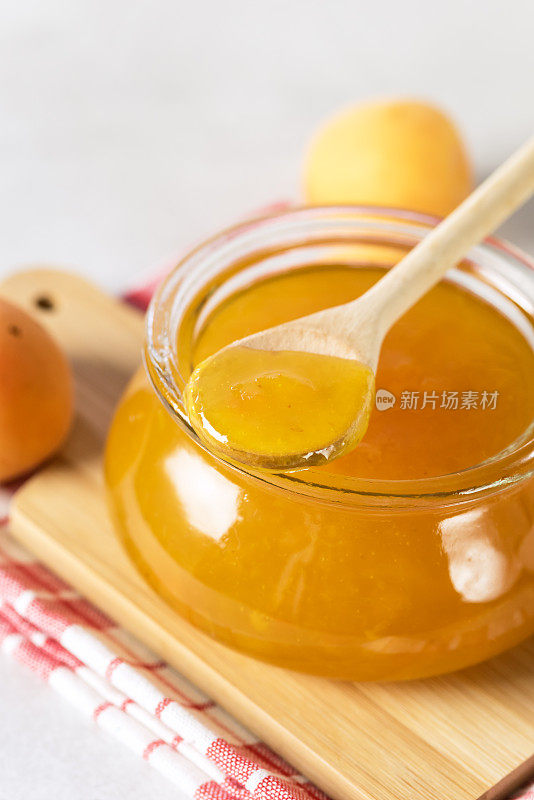 美味新鲜的杏酱装在玻璃罐里，木盘上，餐巾，木勺，竖直上方