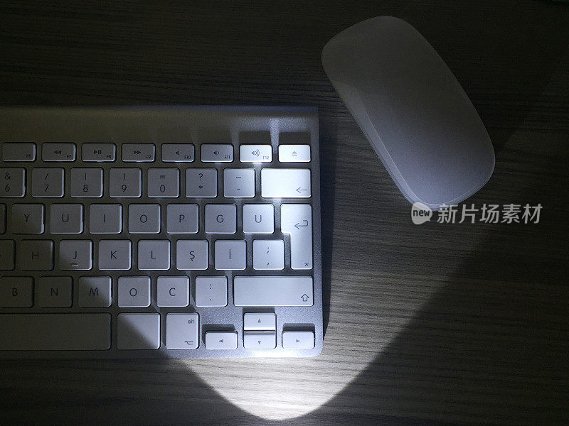电脑键盘和鼠标在黑暗中被聚光灯照亮