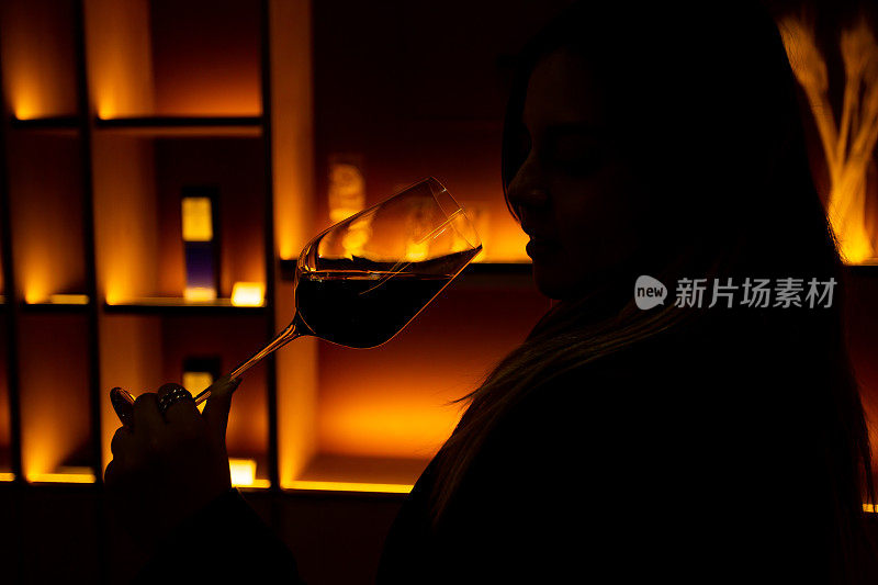 一个品酒师在她的酒杯里闻到红酒的背光。