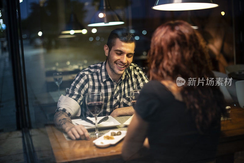 情人节约会在蓝色时间晚上在餐馆吃饭。男人和女人谈笑风生