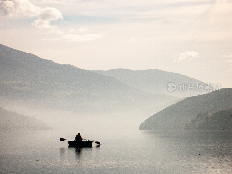 晨雾中，山中的湖面上，渔夫的剪影
