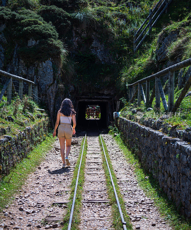 在西班牙阿斯图里亚斯，一个年轻人沿着采矿铁路的轨道走向一个老煤矿的隧道。