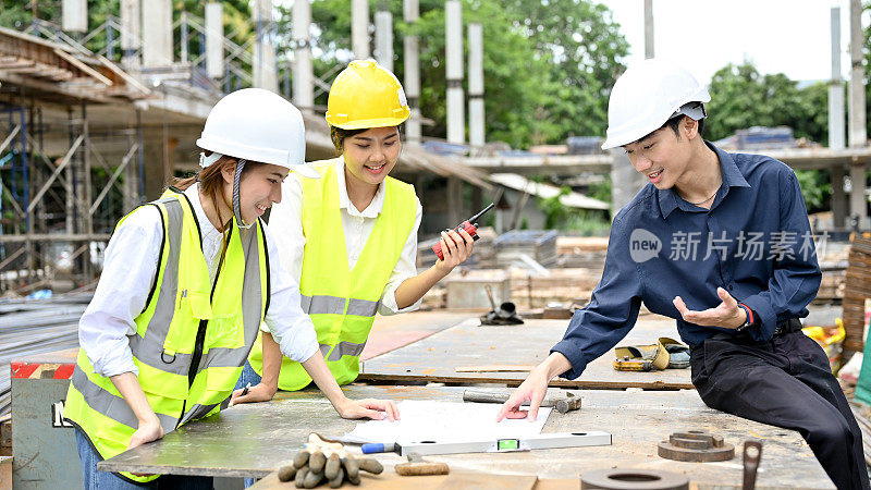 专业的亚洲土建工程师团队在施工现场看图纸。