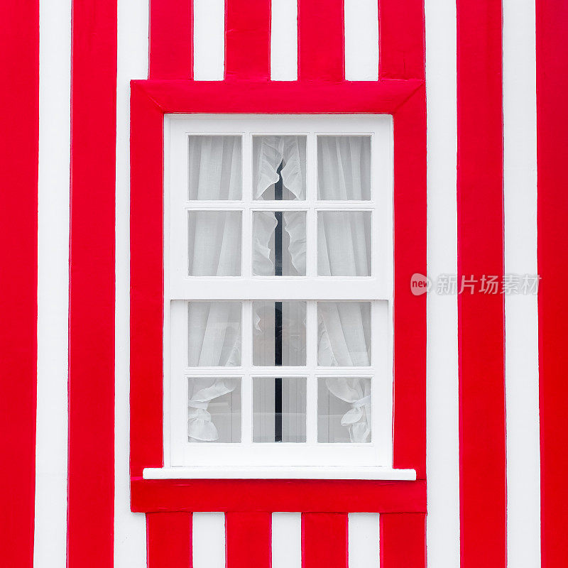 白色边框的老木窗，背景是红白相间的条纹墙。葡萄牙的窗户。葡萄牙房屋的外观