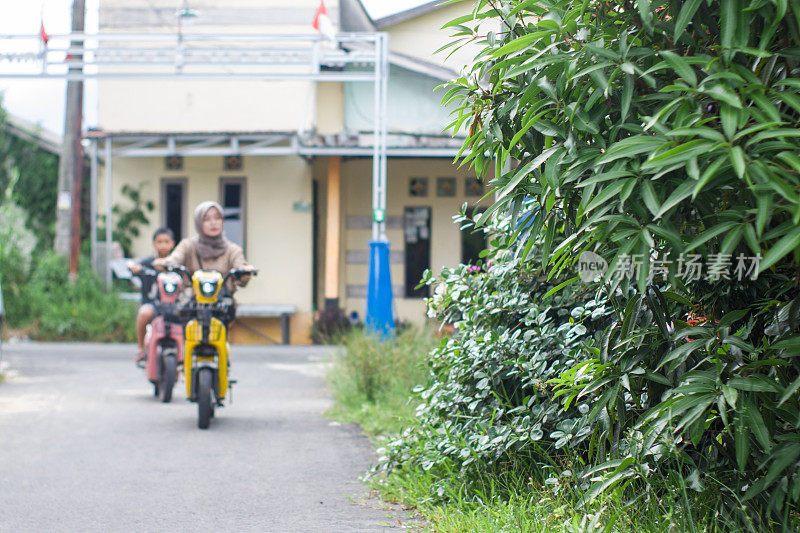 男孩和姐姐在小区骑电动自行车，一起出去玩