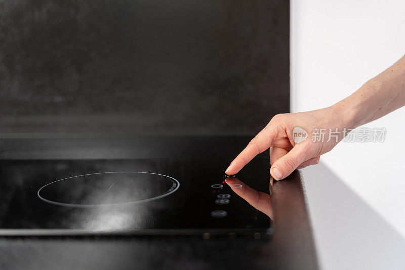 女人按下厨房电炉上的按钮