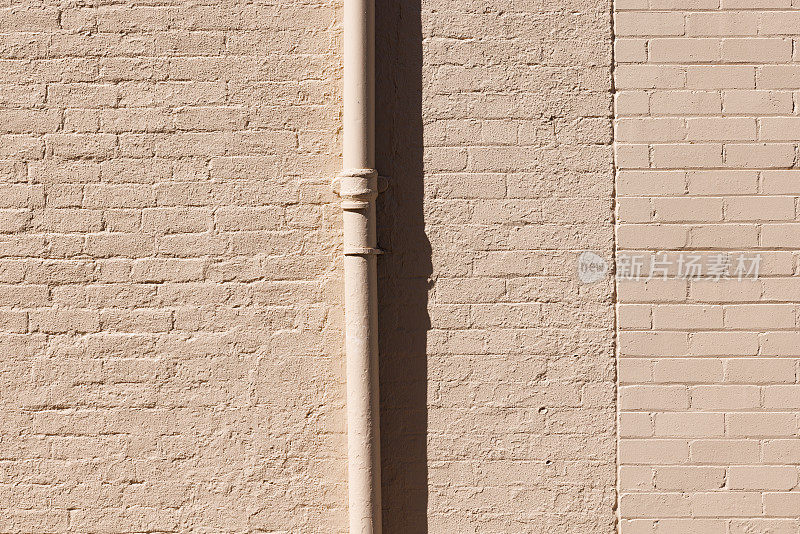 粉刷过的米色老砖墙的一部分，还有一根金属管