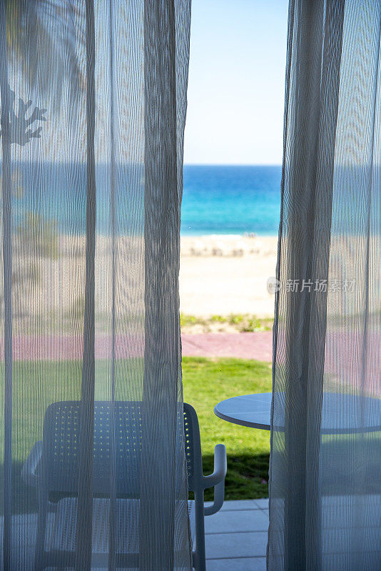 窗帘在风中，可以看到棕榈树和海滩