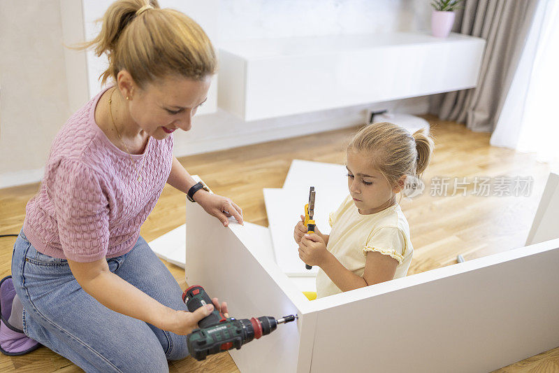 妇女用工具组装家具，照顾女儿，面带微笑