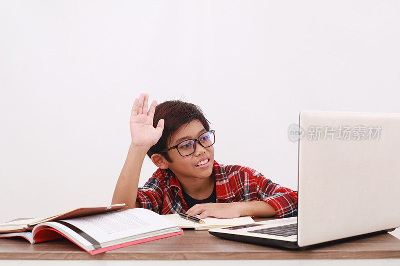快乐的亚洲学生在用笔记本电脑在线学习时举手。孤立于白色